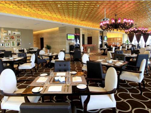 a restaurant with tables and chairs and a chandelier at Zhangjiagang Zhonglian GDH International Hotel in Zhangjiagang