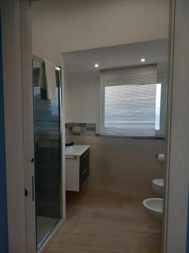 a bathroom with a sink and a toilet and a window at Blueinfinityroom in Pizzo