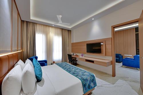 a hotel room with a bed and a flat screen tv at The Orchid Jamnagar in Jamnagar