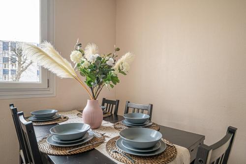 une table avec des assiettes et un vase avec des fleurs. dans l'établissement Le Paisible ~ Centre-ville ~ Arrivée autonome, au Mans