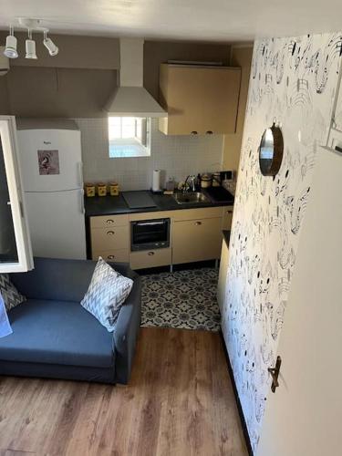 un salon avec un canapé bleu dans une cuisine dans l'établissement Coquette maison de ville au centre du village - V0787, à Vias