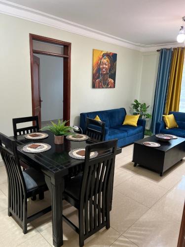 a living room with a table and a blue couch at Kamona Living 3 Zimmer Apartment in Namugongo