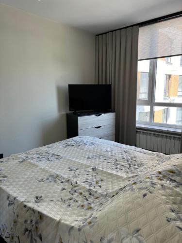 a bedroom with a bed and a flat screen tv at Marseille Apartment in Chişinău