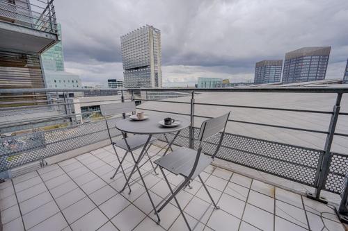une table et des chaises sur un balcon avec vue sur l'eau dans l'établissement Le Panoramique ~ Euralille ~ Arrivée Autonome, à Lille
