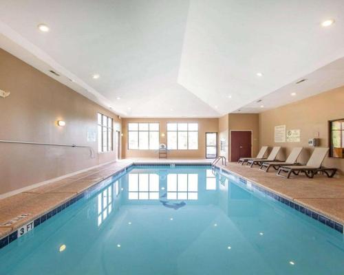 a large swimming pool in a hotel with chairs at Comfort Suites in Rome