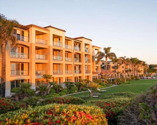 a large yellow building with palm trees and flowers at Dolphin Bay Resort and Spa in Pismo Beach