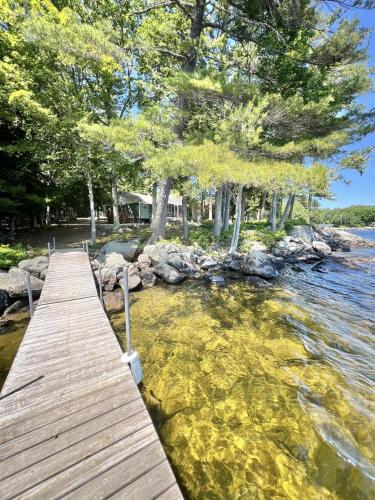 a wooden bridge over a body of water with trees at PLACYD PINES LIMIT 8 cottage in North Sebago