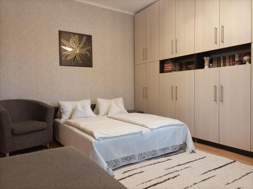 a bedroom with a bed and a chair and a cabinet at Krisztinusz Vendégház in Fonyód