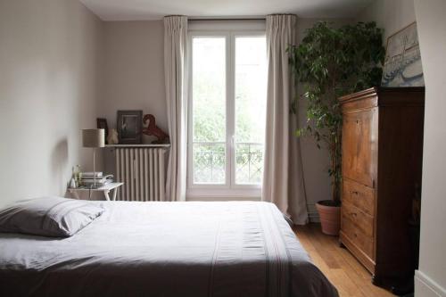 une chambre avec un lit et une grande fenêtre dans l'établissement So Cute 55m2 And Quiet With A Courtyard Garden, à Paris