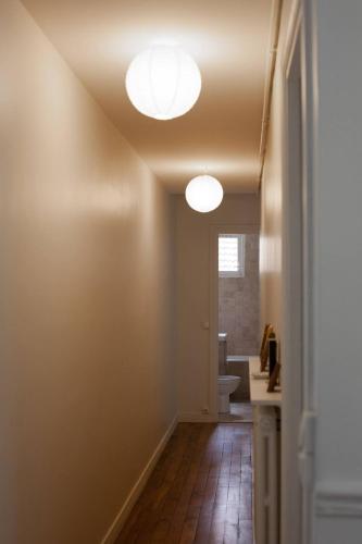 un couloir avec une salle de bain avec WC et deux luminaires dans l'établissement So Cute 55m2 And Quiet With A Courtyard Garden, à Paris