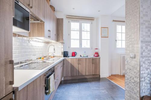 une grande cuisine avec des placards en bois et un évier dans l'établissement Le Parisien ~ Champs Elysées ~ Métro, à Neuilly-sur-Seine
