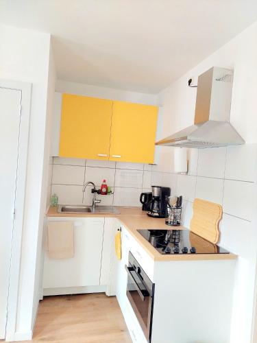 a kitchen with white counters and yellow cabinets at Maison LYDIE - Meublé de vacances 3 étoiles in Charleroi