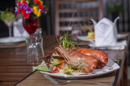 a plate of food on a wooden table at Sapphire Seas Beachfront Hotel in Hikkaduwa