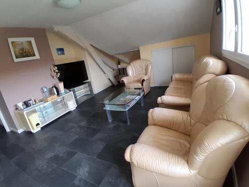 a living room with a couch and chairs and a tv at CHAMBRES D HÔTES AU P'TIT BONHEUR CAMPAGNARD in Jarnosse