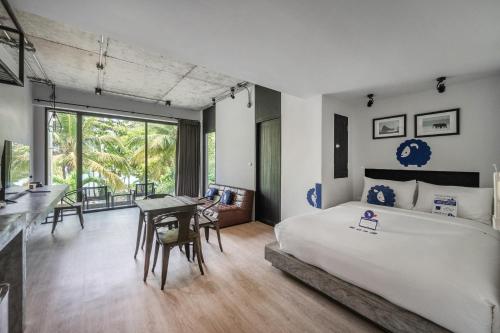 a bedroom with a bed and a desk and a table at Kokotel Khao Lak Lighthouse in Khao Lak