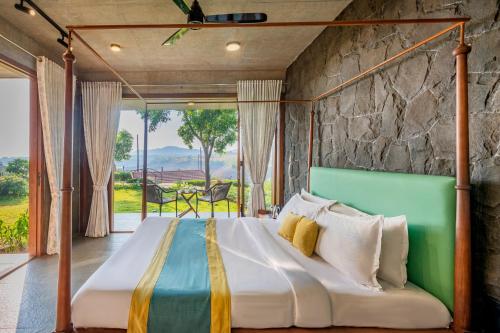 a bed in a room with a stone wall at SaffronStays Avni in Trimbak