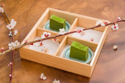 two pieces of green cake in a wooden box with flowers at FARMSTAY miyuki-street "Hotaru" in Kugumiya