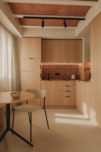 a kitchen with wooden cabinets and a table and chair at Pau Suites in Villajoyosa