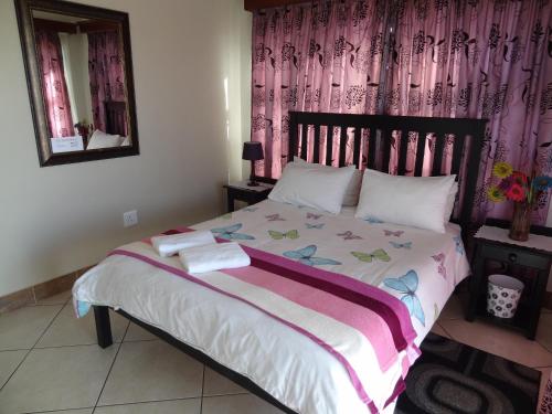 a bedroom with a large bed with pink curtains at Apartment Chianti's in Port Edward