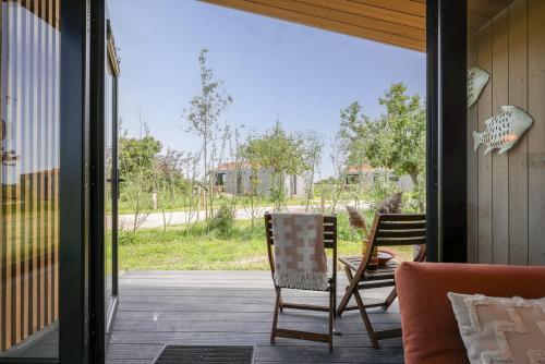 un patio con 2 sillas y una mesa en un porche en Hello Zeeland - Tiny House Zeeuwse Liefde 13, en Westkapelle