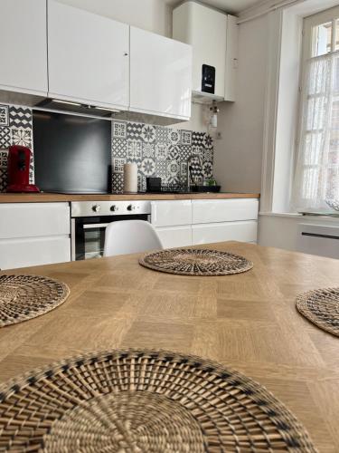 une cuisine avec une table en bois et des armoires blanches dans l'établissement KerKolina, à Cancale