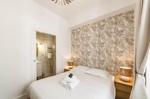 une chambre avec un lit blanc et un mur dans l'établissement La palmeraie AIL, à Villeurbanne