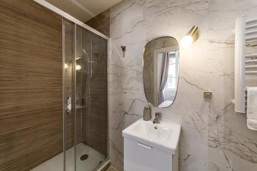 une salle de bain avec un lavabo, une douche et un miroir dans l'établissement La palmeraie AIL, à Villeurbanne