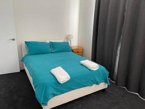 a bedroom with a blue bed with two towels on it at Coastal Escape on Prevelly in Jurien Bay