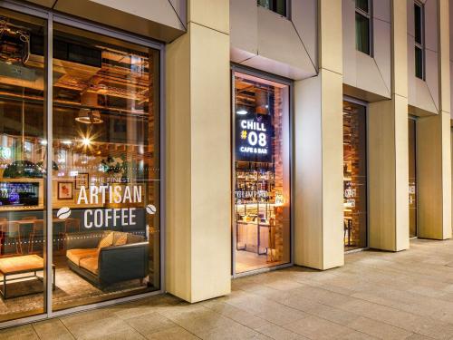 a coffee shop with a sign in the window at ibis London Canning Town in London