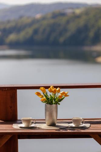 a table with two cups and a vase with flowers at Tarasy nad Solina in Zawóz