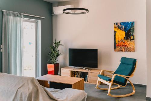 a living room with a tv and a blue chair at Charys Premium Home in Preveza