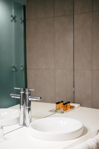 a bathroom with a white sink and a mirror at Macarico Beach Hotel in Praia de Mira