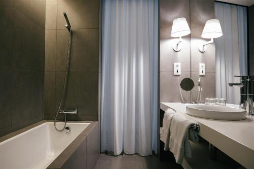 a bathroom with a tub and a sink and a bath tub at Macarico Beach Hotel in Praia de Mira