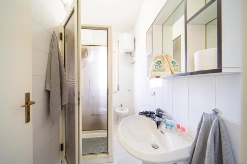 a white bathroom with a sink and a shower at Appartamento Fronte Mare in Marina di Strongoli