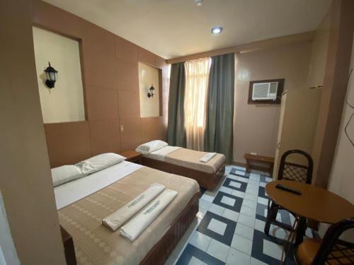 a hotel room with two beds and a table at Bamboo Garden Bussiness Inn in Dipolog
