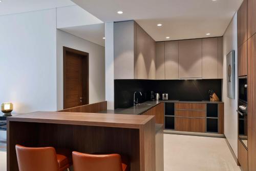 a kitchen with brown cabinets and a counter with orange chairs at Conrad Bahrain Financial Harbour in Manama