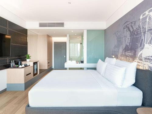 a bedroom with a large white bed and a kitchen at Novotel Phnom Penh BKK 1 in Phnom Penh