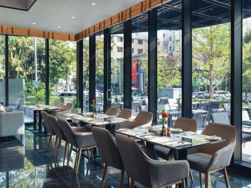 a row of tables in a restaurant with windows at Novotel Phnom Penh BKK 1 in Phnom Penh