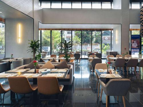 a dining room with tables and chairs and windows at Novotel Phnom Penh BKK 1 in Phnom Penh