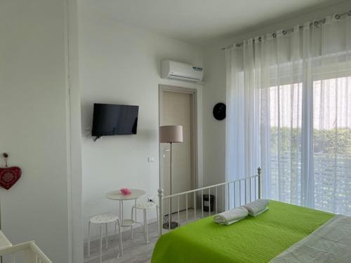 a white bedroom with a green bed and a table at Villa Jolanda in Citta' Sant'Angelo