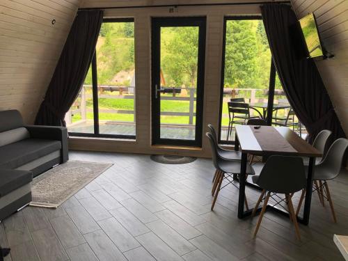 a living room with a table and chairs and windows at Soul House in Pilipets