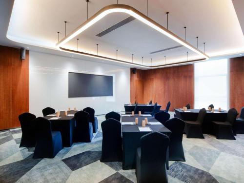 a conference room with tables and chairs and a projection screen at Novotel Nanjing Airport in Nanjing