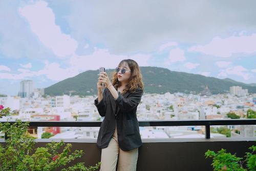 a woman taking a picture of a city with her cell phone at Joi Hospitality - Central in Vung Tau