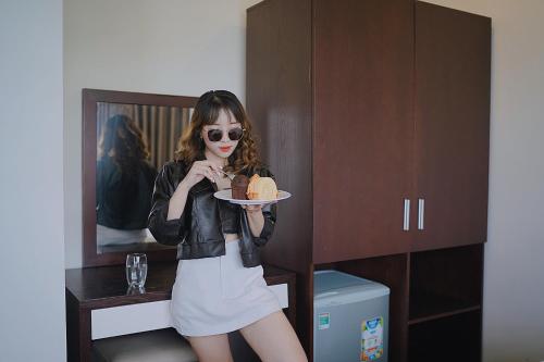 a woman holding a plate with a piece of cake at Joi Hospitality - Central in Vung Tau