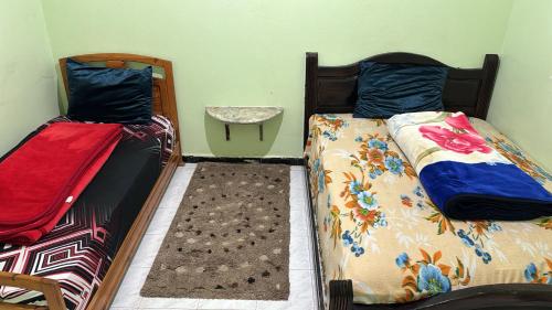 two twin beds in a room with a table at Appartement Ayman in Khemisset