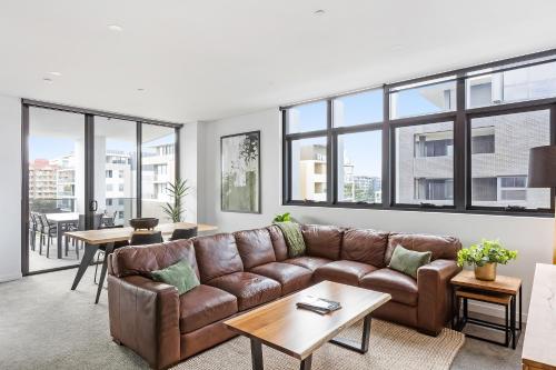 a living room with a couch and tables and windows at Astra Apartments Wollongong Beatson Street in Wollongong