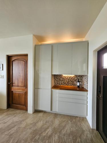 a kitchen with white cabinets and a wooden door at Casa Aramana in Vieques