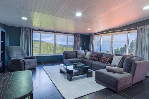a living room with a couch and chairs and windows at GuestReady - Quinta das Estrelas in Campanário