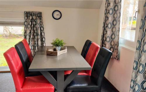 a dining room table with red chairs and a clock at Three-Bedroom Holiday Home In Vledder in Vledder