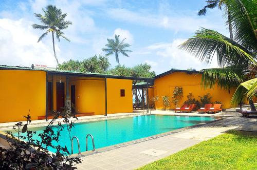 a swimming pool in front of a house with palm trees at The Beach Cabanas Retreat & Spa in Koggala